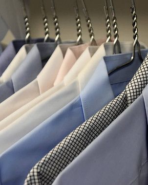 Shirts on hangers, varying pastel colors. Close-up view in a closet, angled perspective.