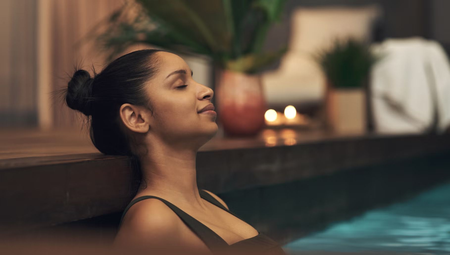 Woman relaxing in a pool with eyes closed, leaning against the edge in a spa setting