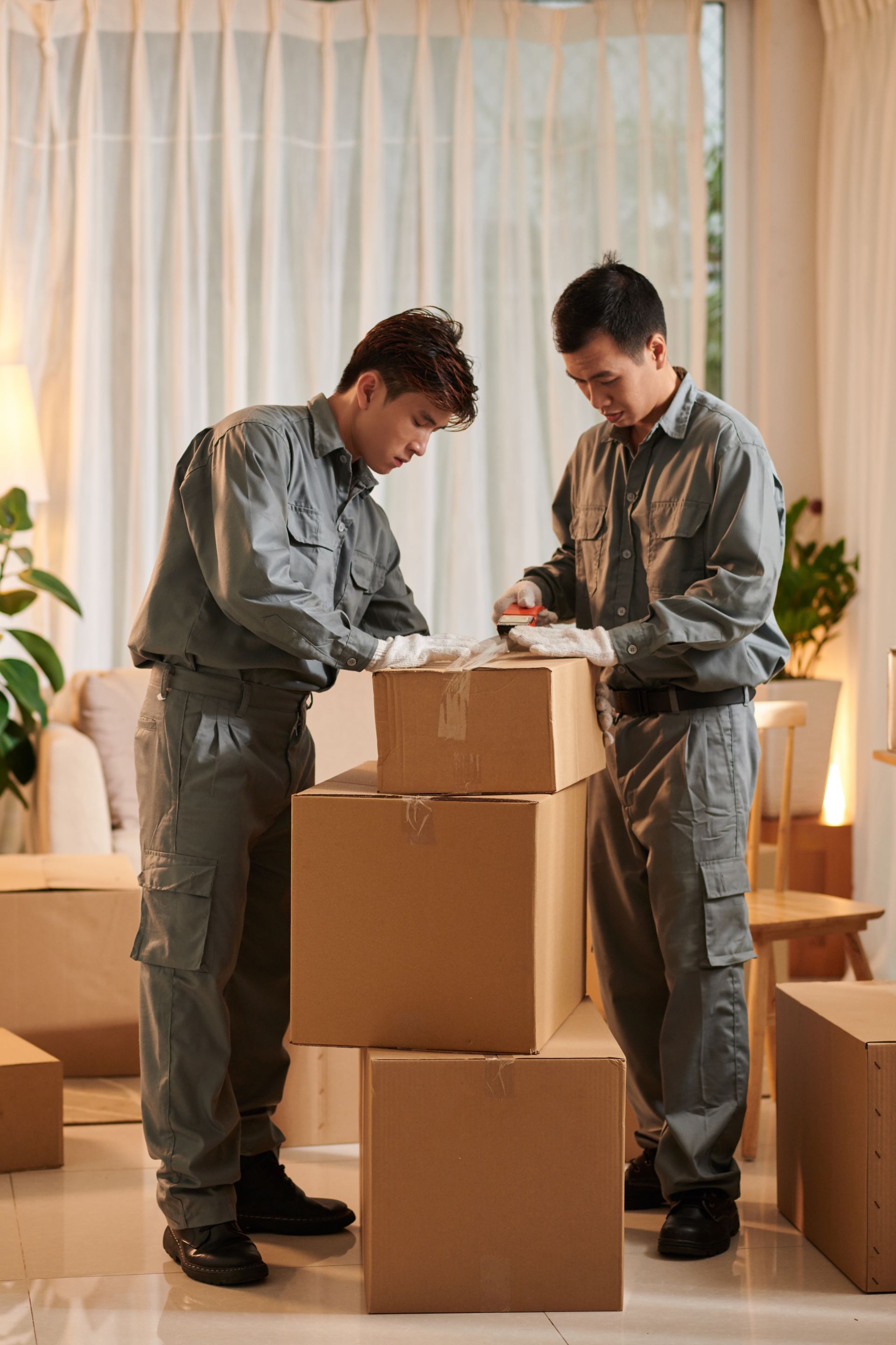 Two men are packing boxes in a living room.