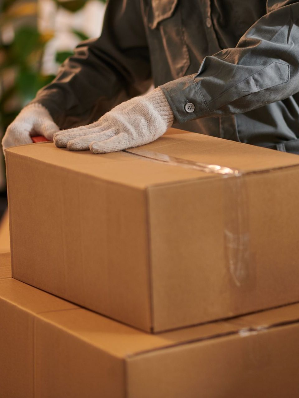 A person is putting a glove on a cardboard box.