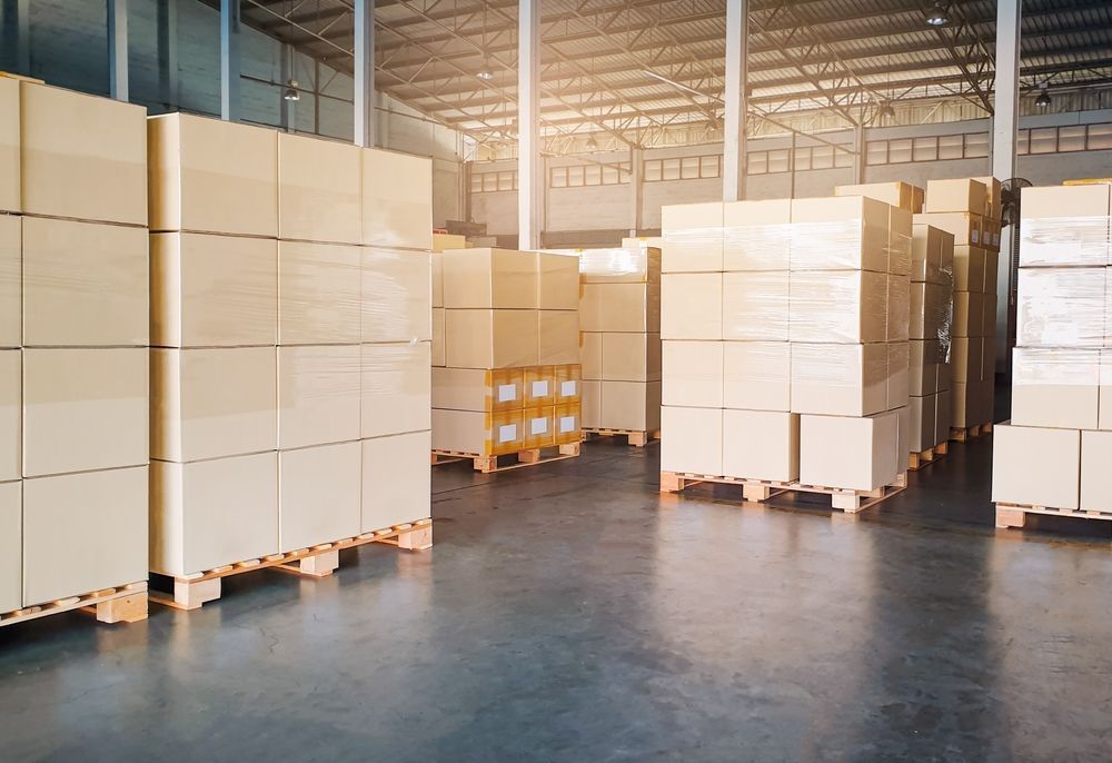 A large warehouse filled with lots of boxes on wooden pallets.