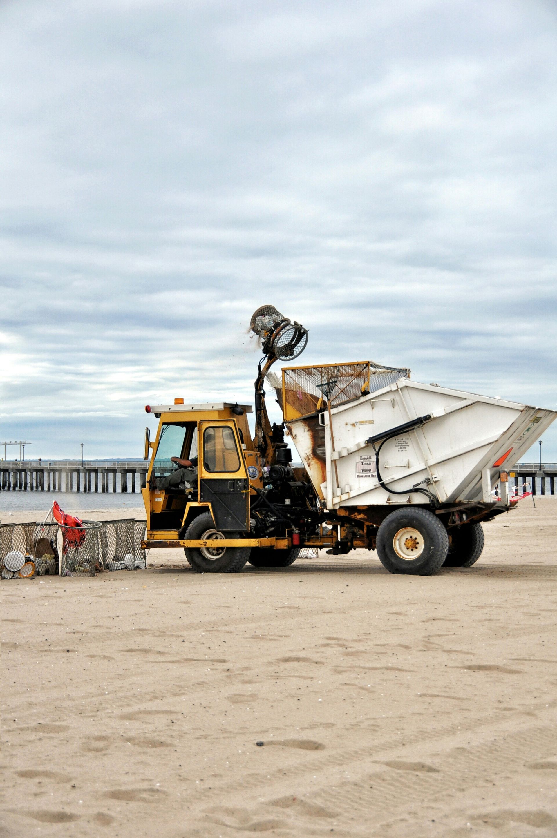 A yellow and white truck is parked on a sandy beach.