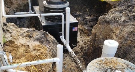 A new septic system being installed; pipes, tanks, and equipment sit in a dirt trench.