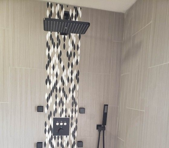 Modern shower with black fixtures, patterned tile accent, and beige walls.