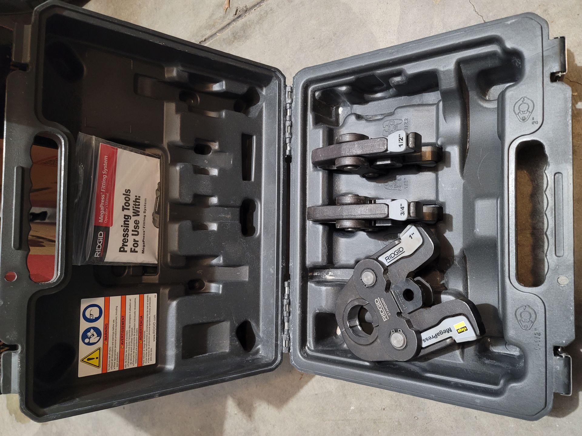 Open gray tool case with pressing tools and instructions.