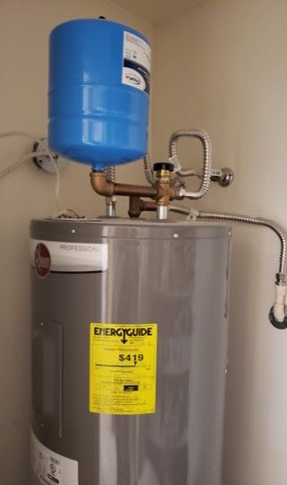 A water heater with a blue expansion tank on top, in a neutral-colored room.