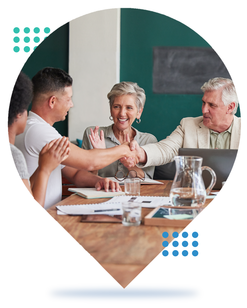 People in a meeting shaking hands around a conference table in a bright office