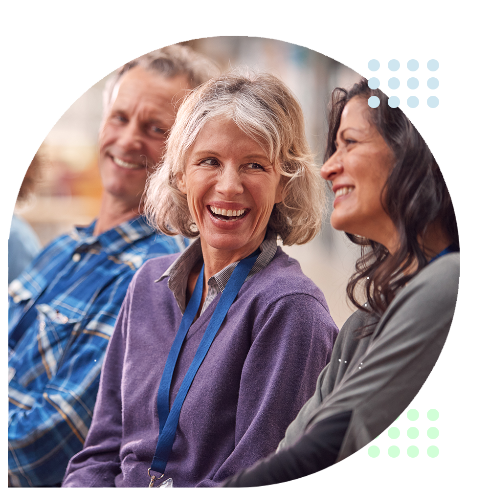 Smiling group seated together in a bright circle-cropped photo, with a purple sweater in the foreground