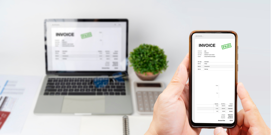 Hand holding a smartphone beside a laptop showing the same document on a desk with a potted plant
