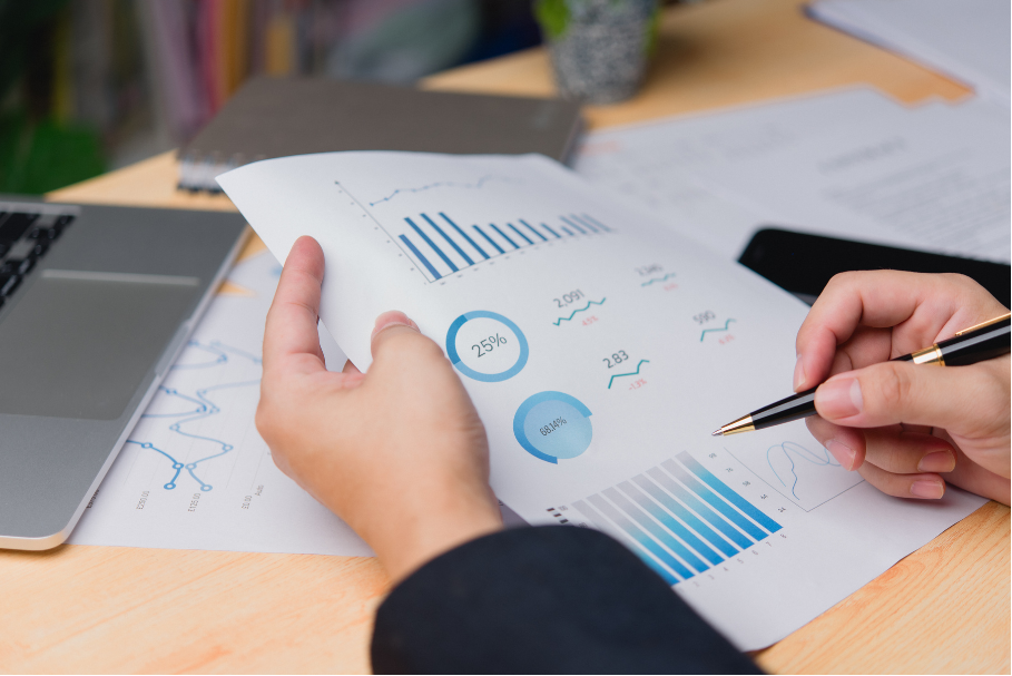 Hands reviewing a report with blue charts and graphs on a desk