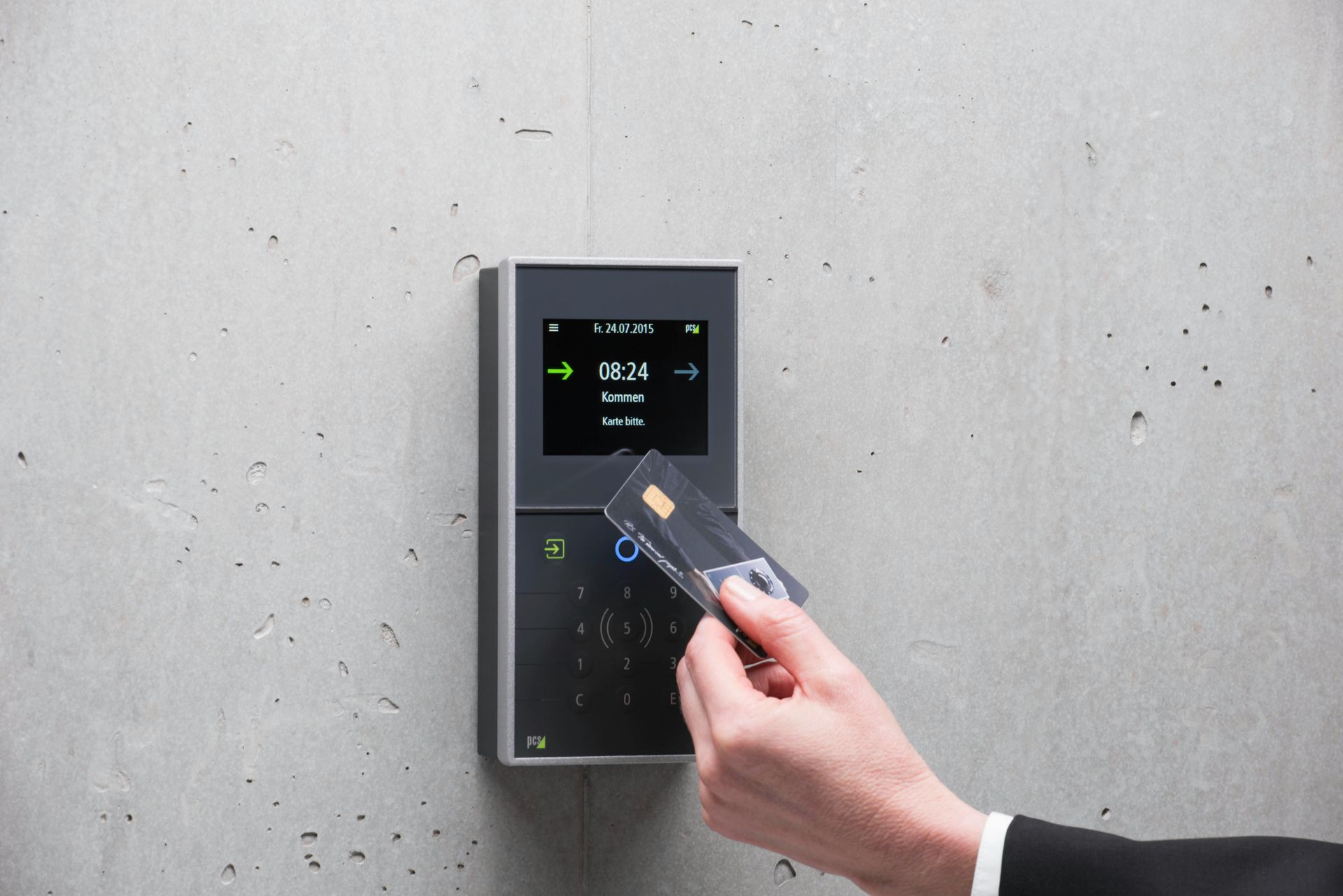 Hand holding a key card to a wall-mounted digital access keypad with illuminated display