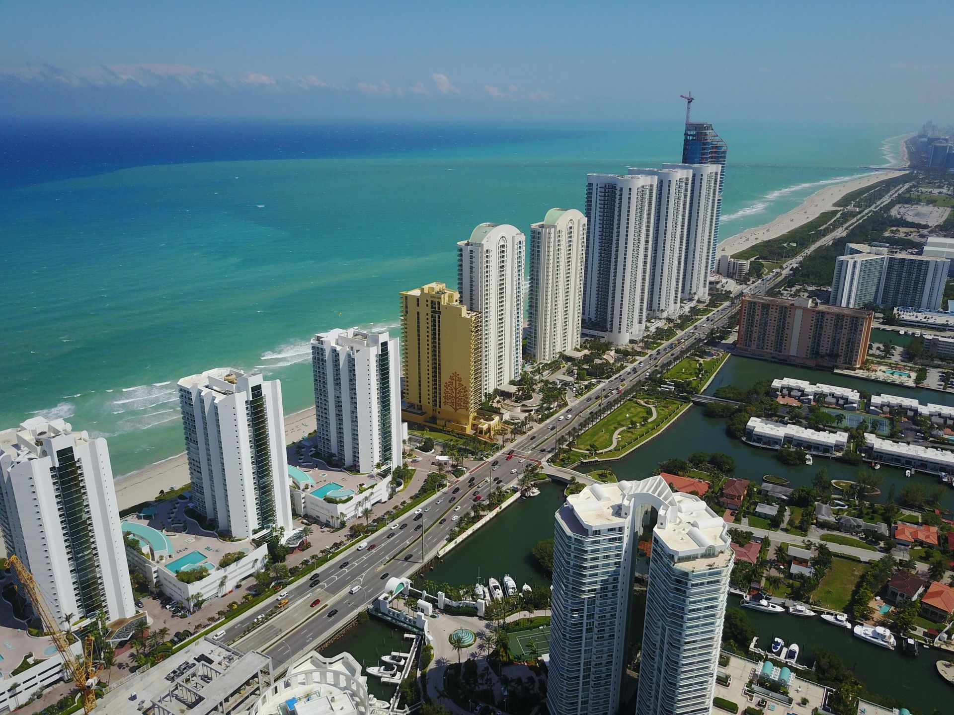 High-rise beachfront condos beside a turquoise ocean and coastal highway