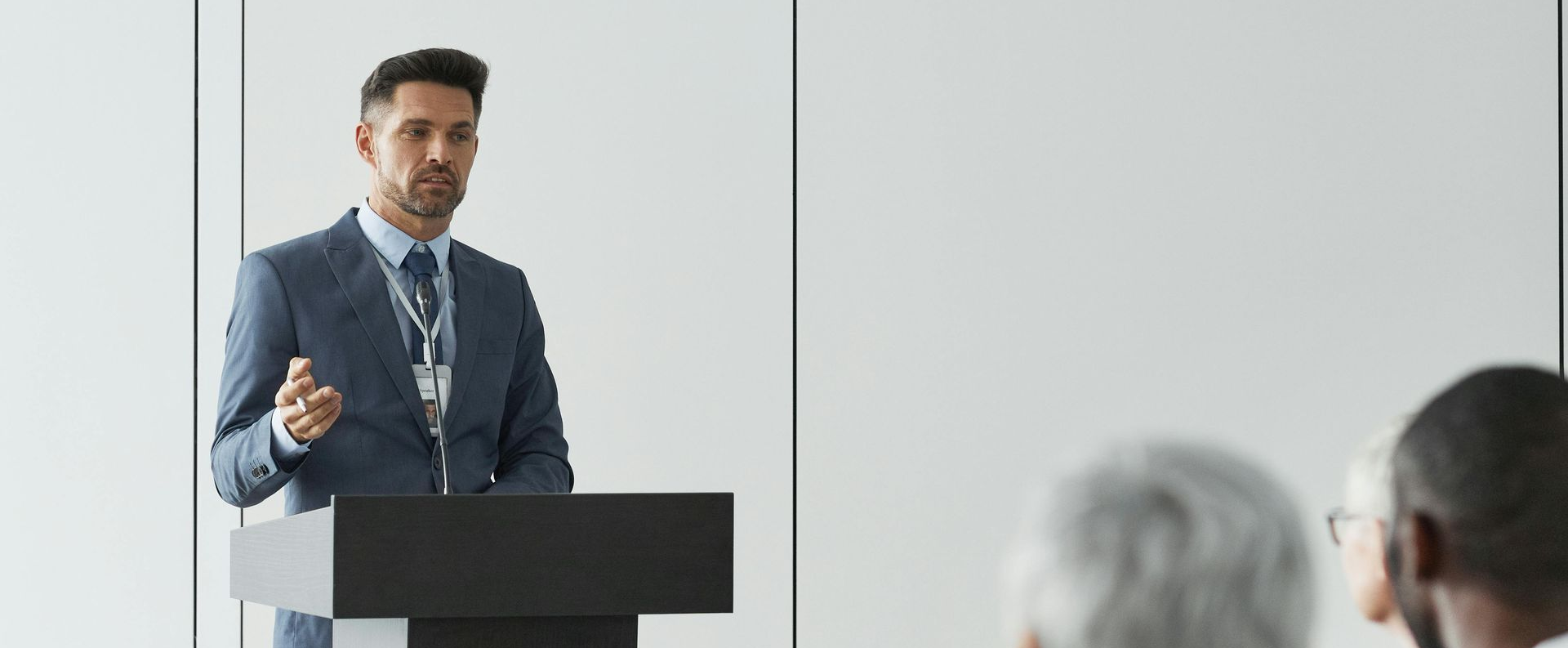 Speaker at podium giving a presentation to an audience in a bright conference room