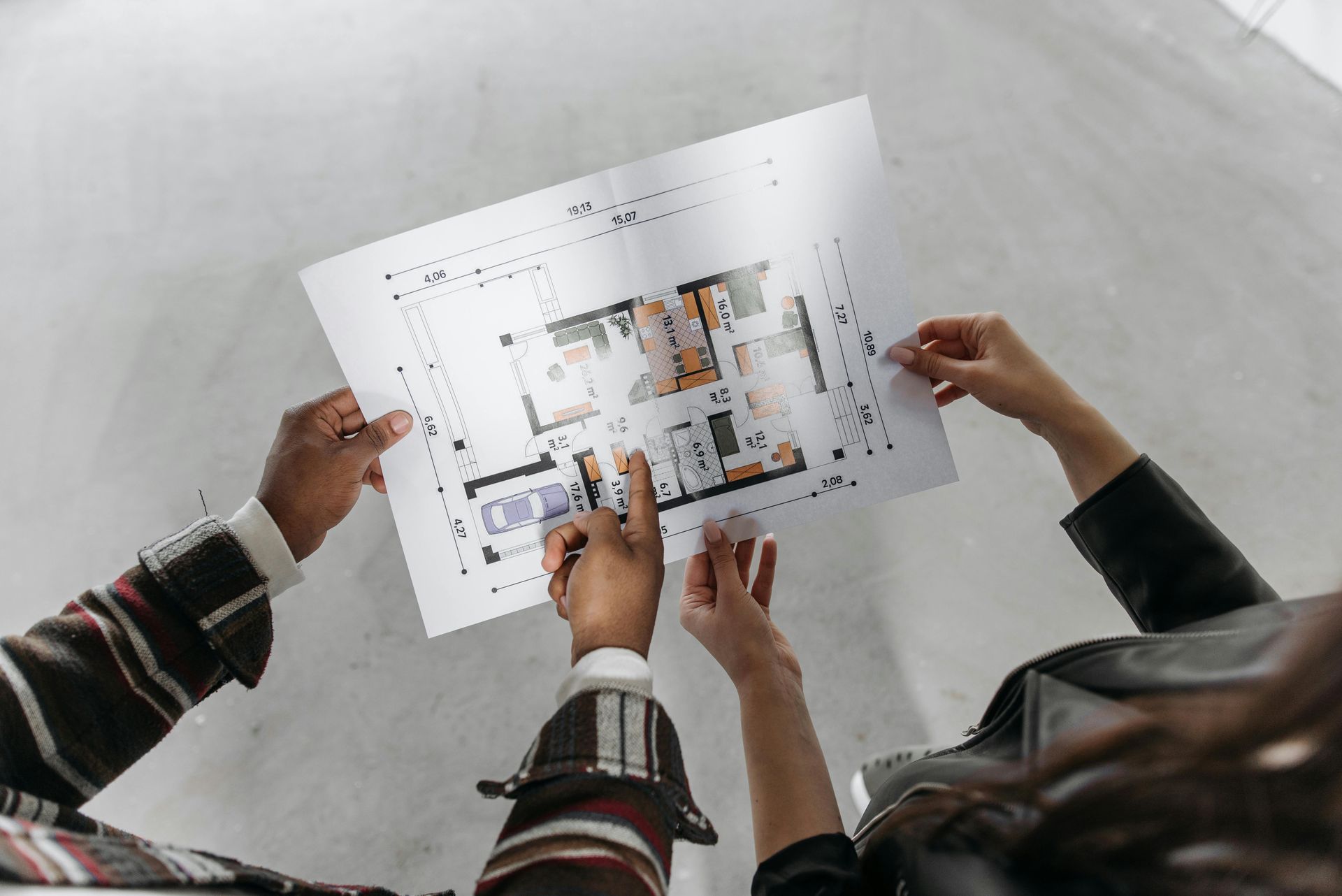 Three hands reviewing a printed floor plan on a table