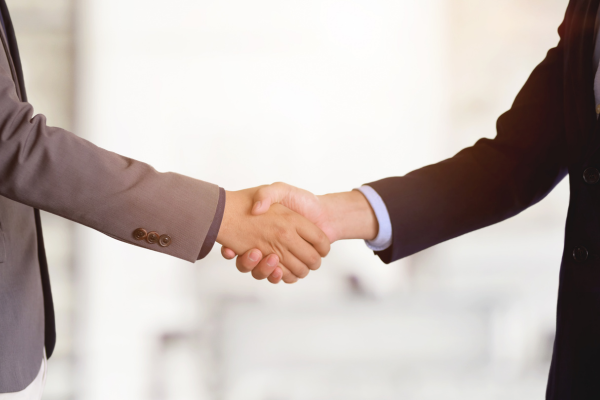 Two professionals shaking hands to build trust | CMO Media Lab