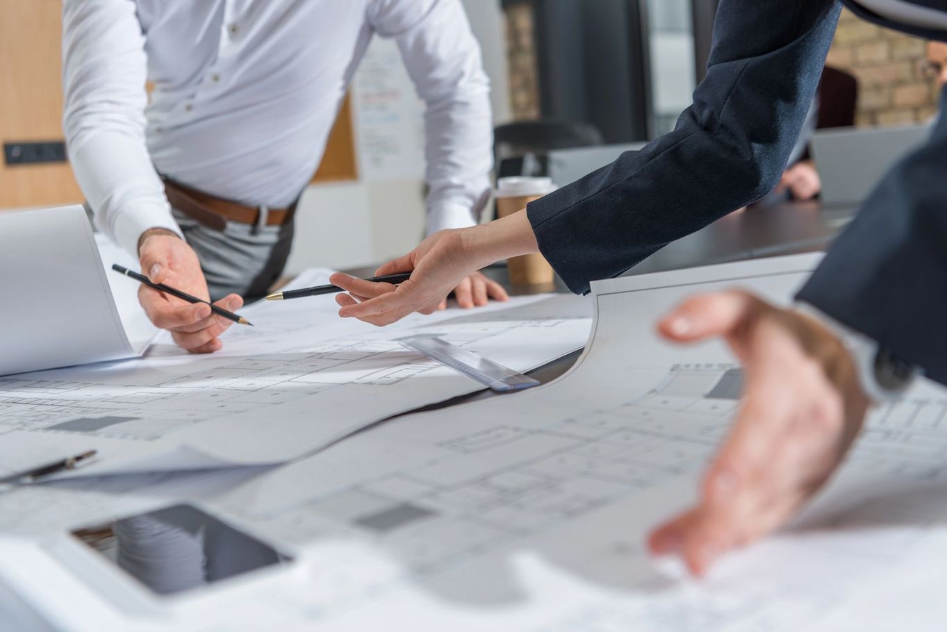 Persone che esaminano i progetti e indicano i piani architettonici su un tavolo
