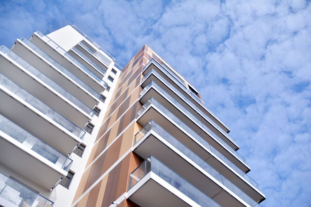 Veduta dal basso di moderni grattacieli residenziali sullo sfondo di un cielo azzurro.