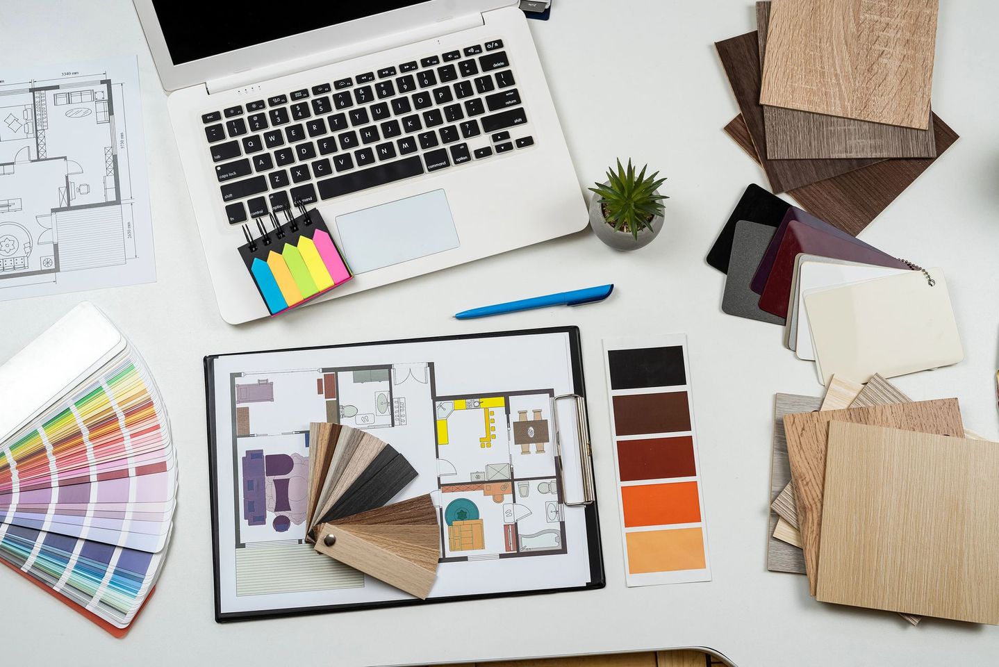 Corridoio con quadri incorniciati, una pianta in vaso e una sedia pieghevole su cui è appoggiato un poster giallo.