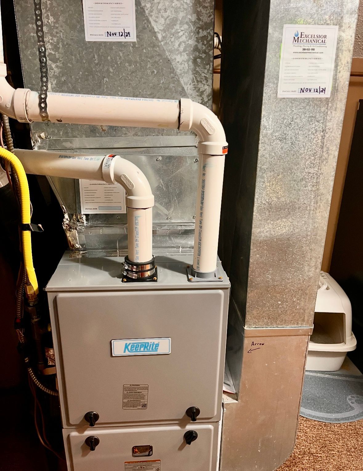 An air conditioner is sitting in a basement next to a cat litter box.