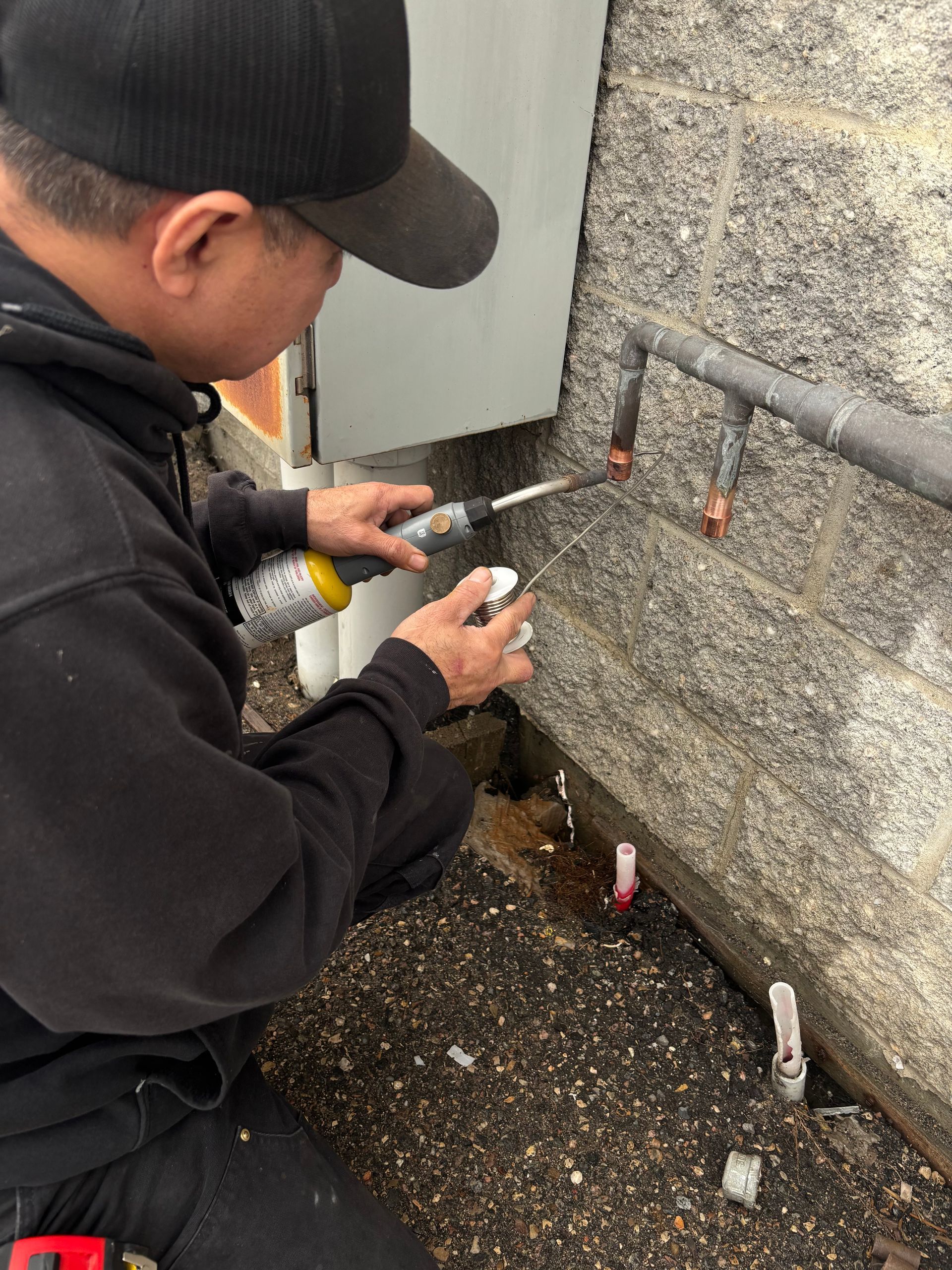 A man is working on a pipe with a screwdriver.