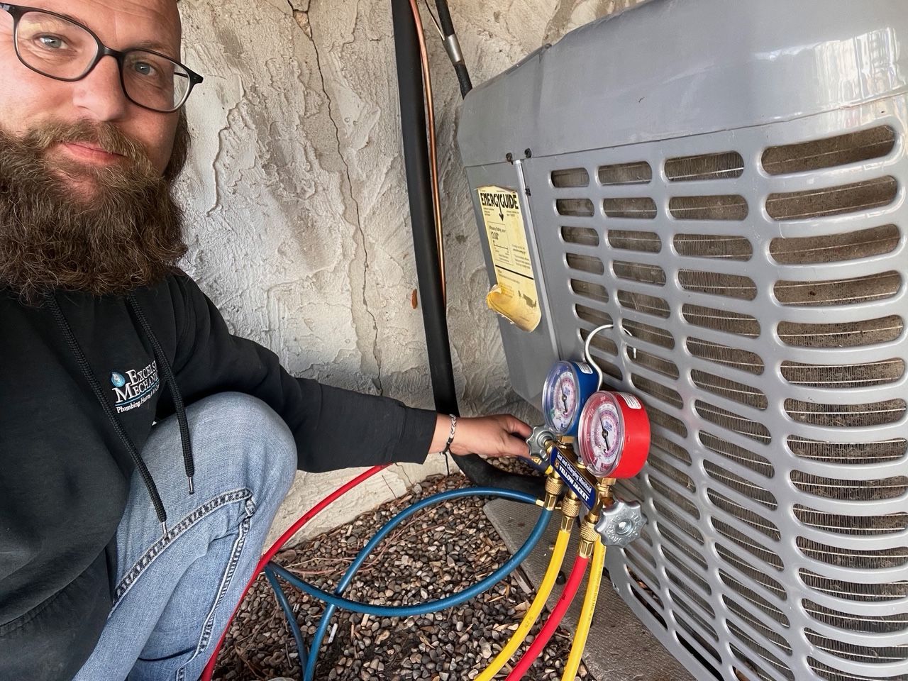 A man with a beard and glasses is working on an air conditioner.