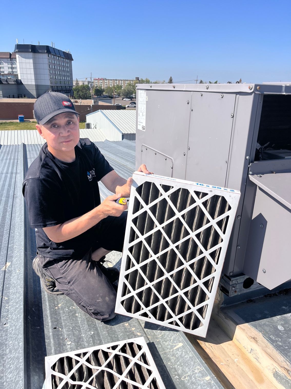 A man is kneeling on a roof holding a filter.
