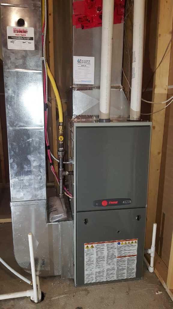 a furnace is sitting in a basement next to a wall .