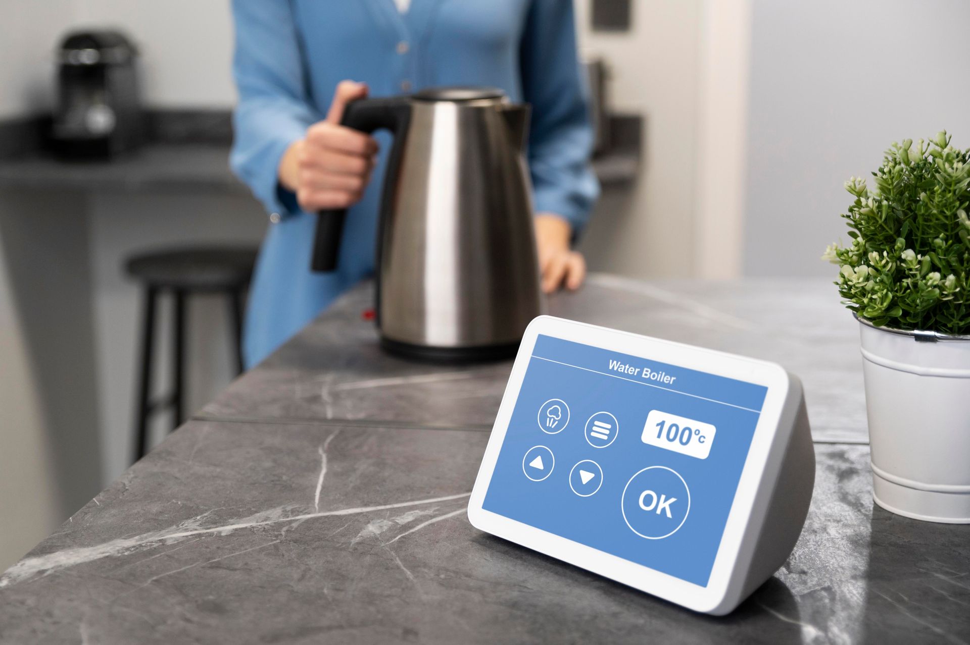 a woman is holding a kettle on a counter next to a smart device .