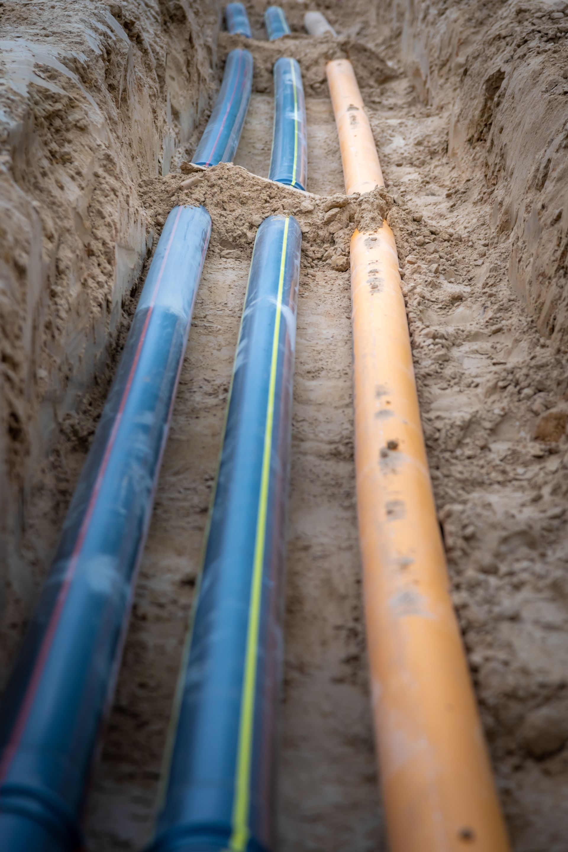 a bunch of pipes are laying in the dirt in a trench .