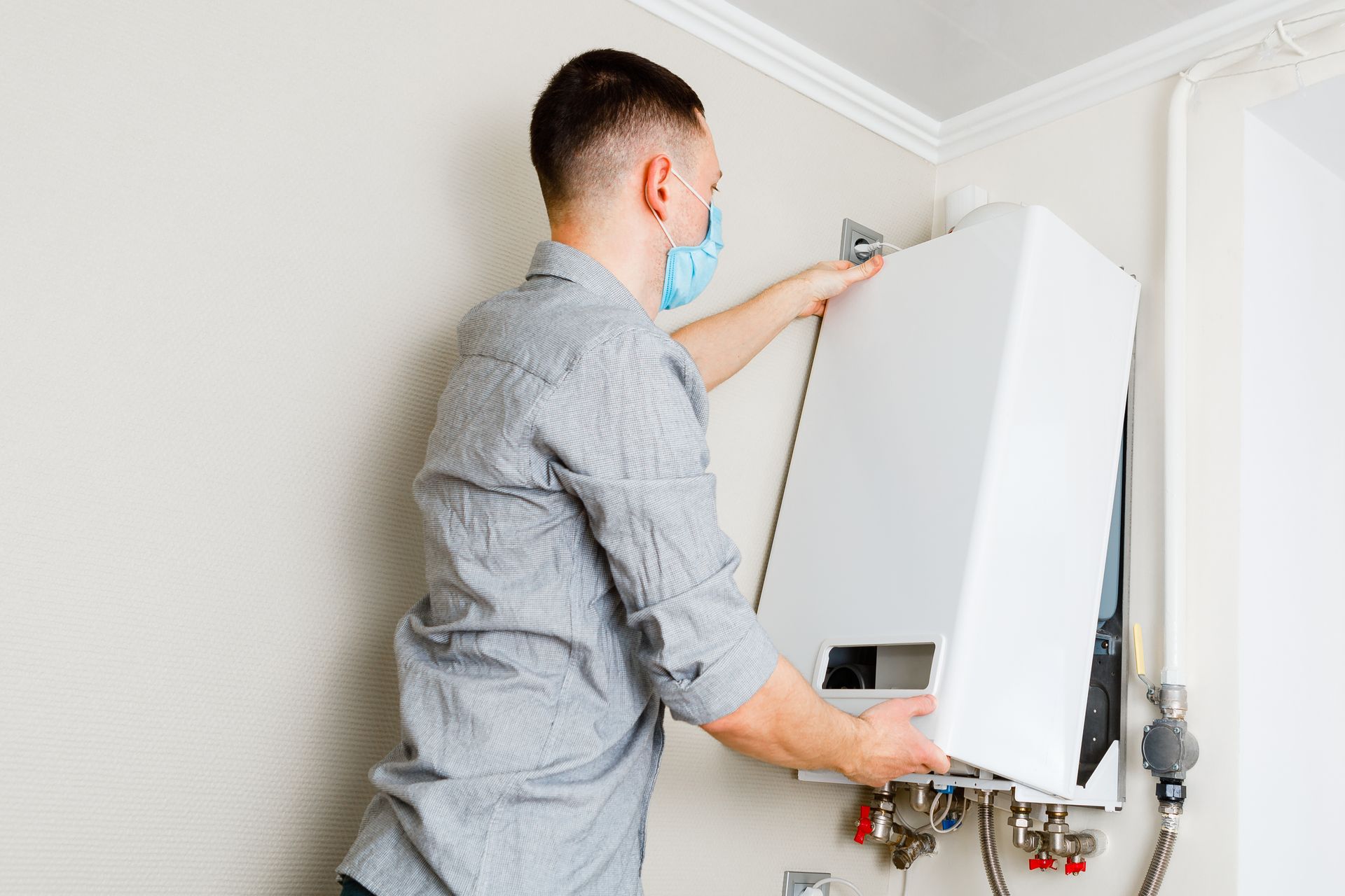 A man wearing a mask is installing a water heater.