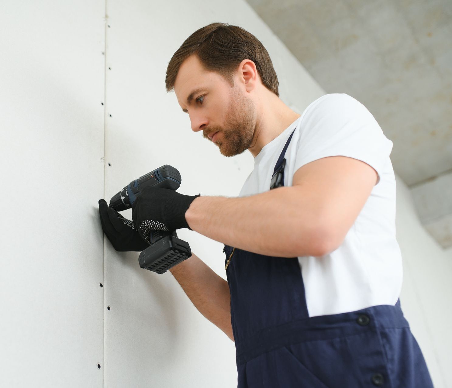 a man is using a drill on a wall .