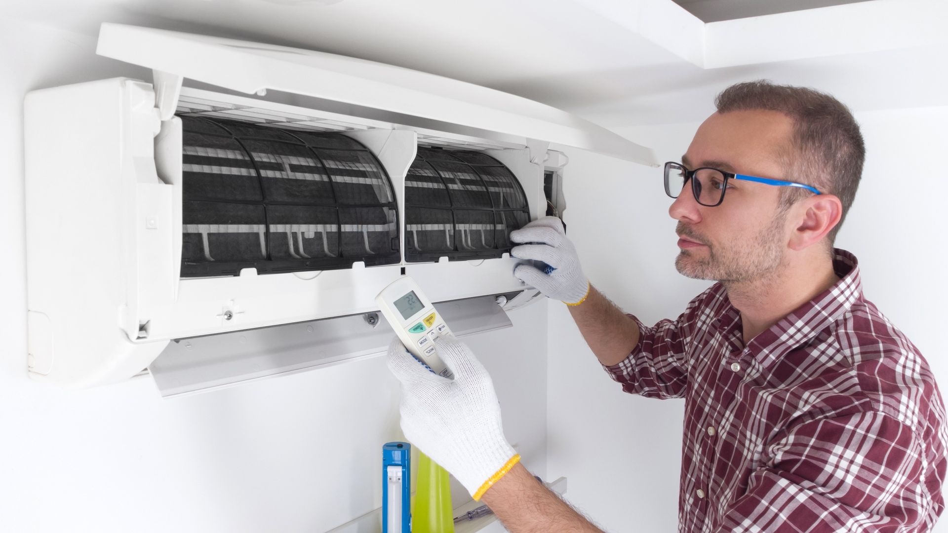 A man is cleaning an air conditioner with a remote control.
