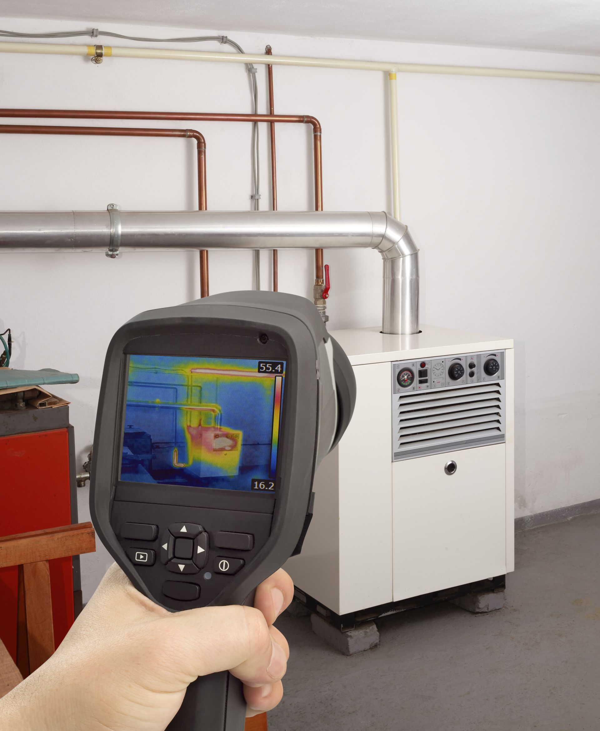 a person is holding a thermal camera in front of a boiler