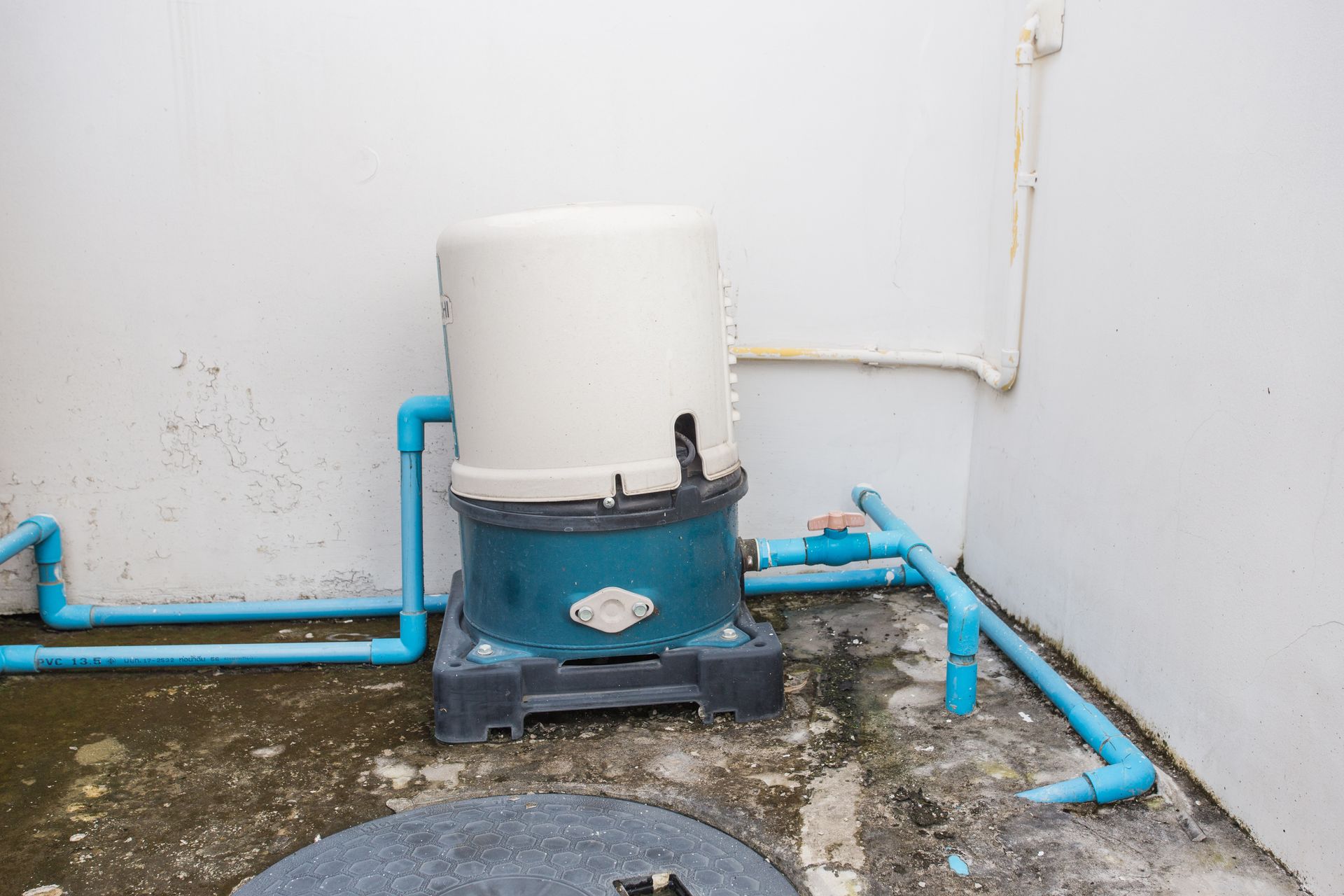 a water pump is sitting in a corner of a room next to a wall .