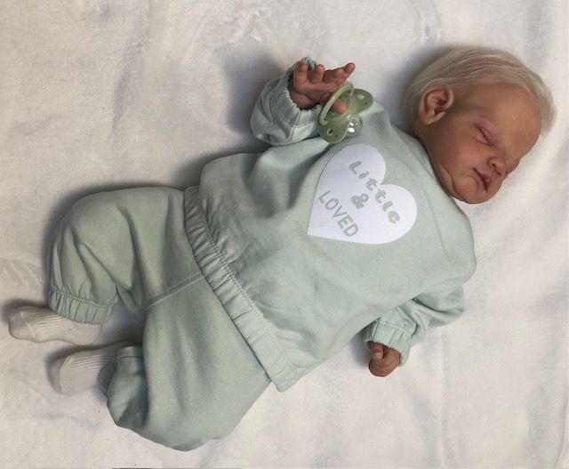 Een babyjoggingpakje met de tekst klein en geliefd, maat 62