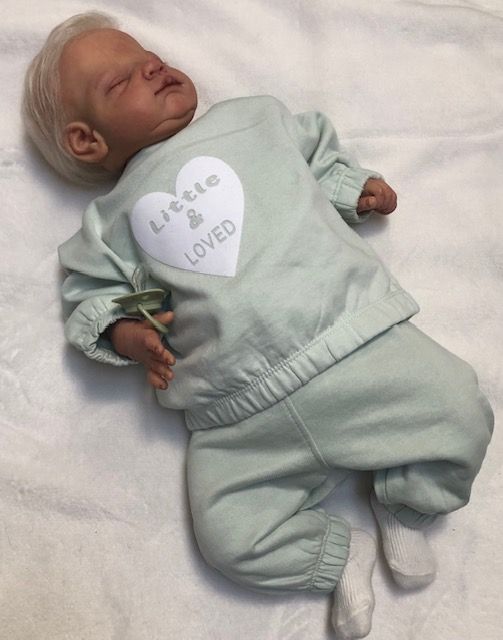 Een babyjoggingpakje met de tekst klein en geliefd, maat 62