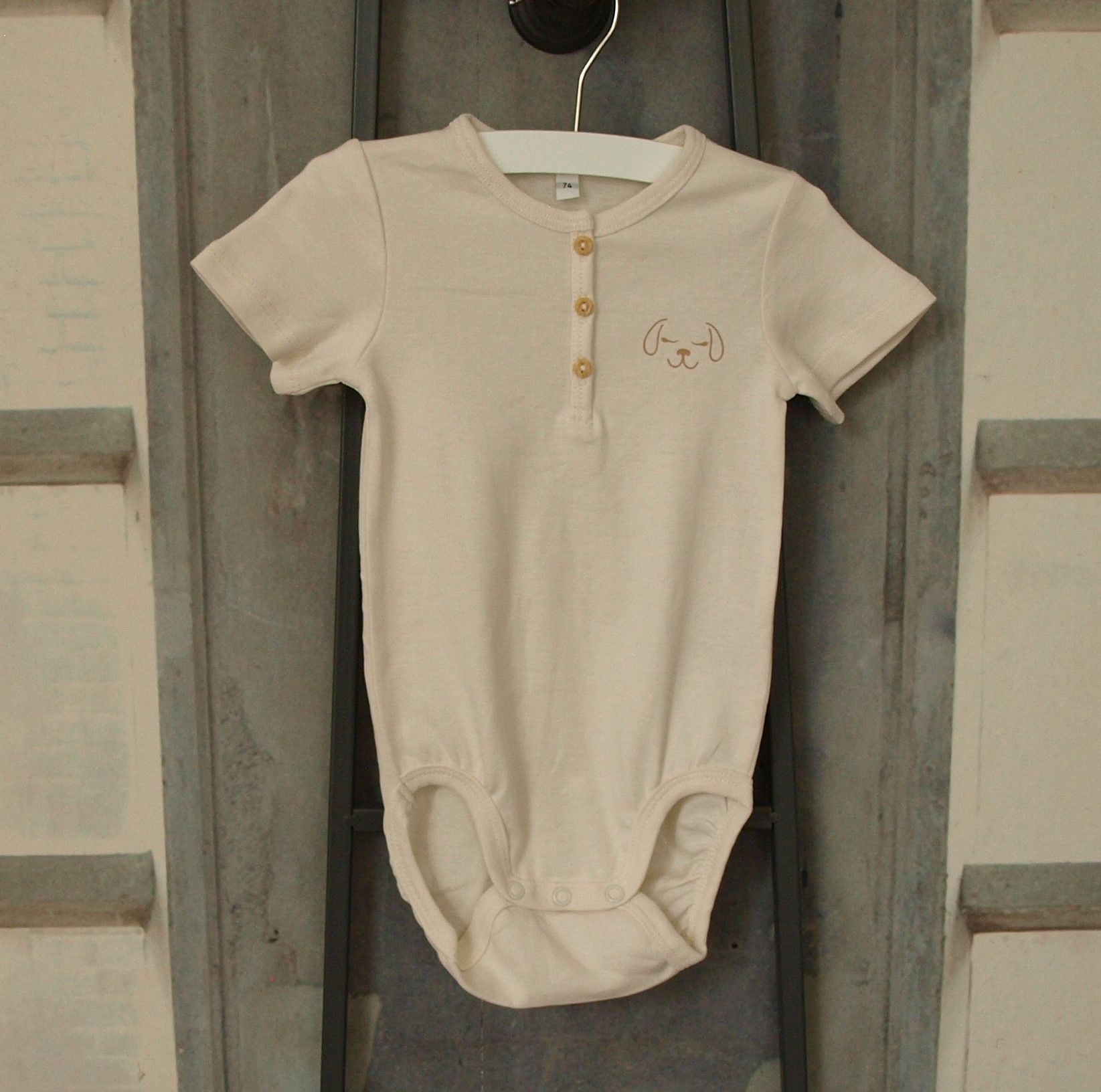 Roomkleurig rompertje, met knoopje, korte mouw en dog, maat 74