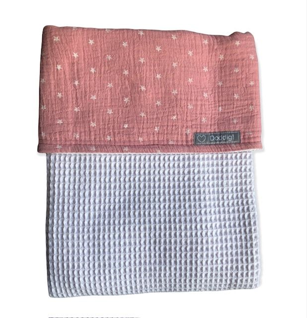 Een roze en wit dekentje en lakentje ineen met witte sterretjes erop, voor kinderwagen en wieg