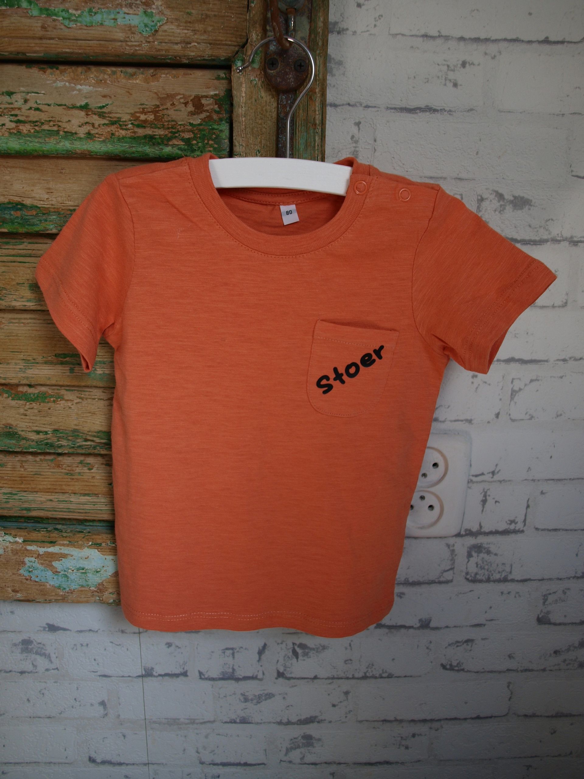 Een oranje t-shirt met daarop de tekst 'stoer', maat 80