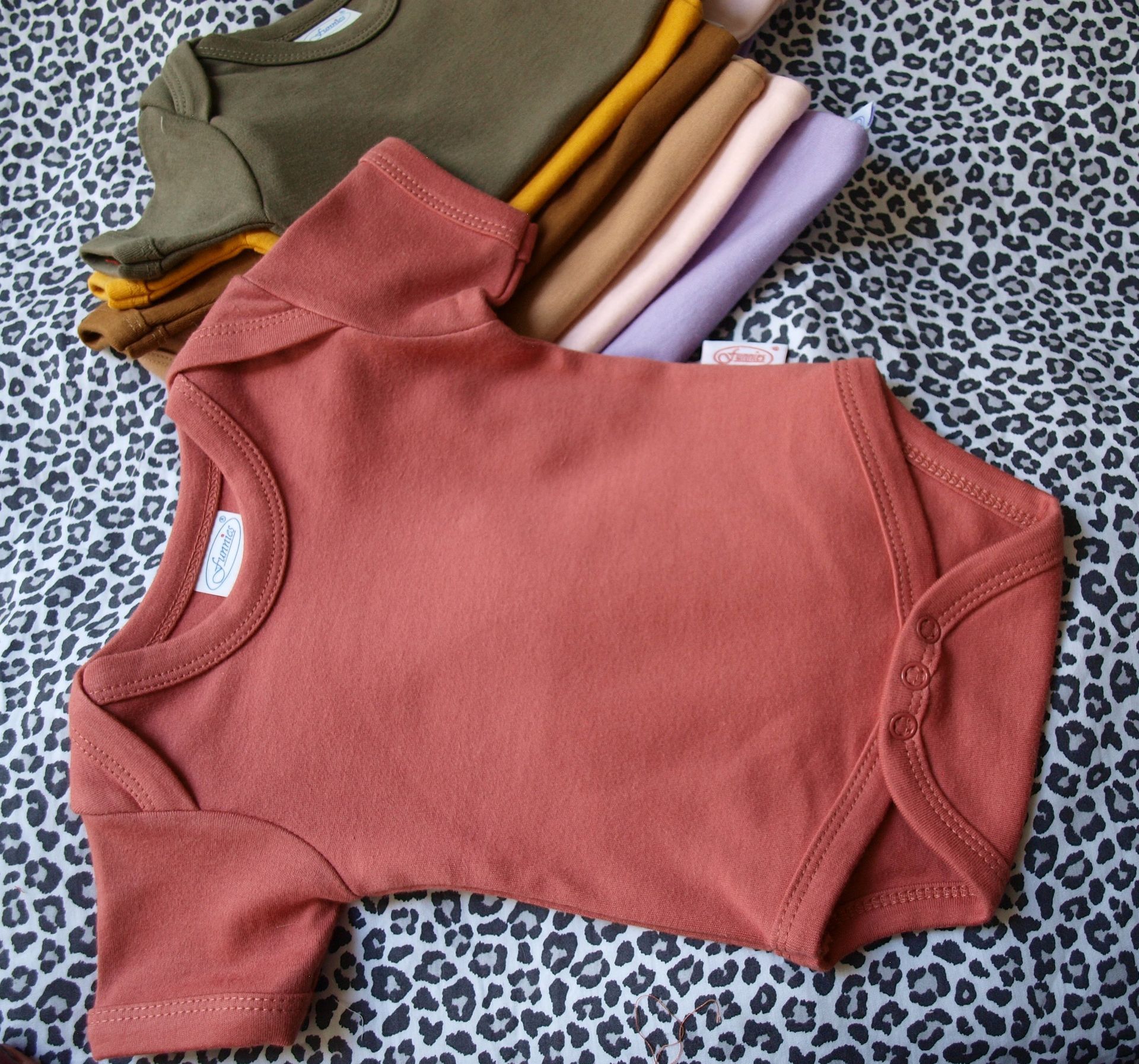 Een klei kleurig baby rompertje met korte mouwen en drukkertjes