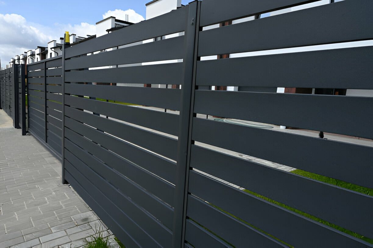 A wooden fence surrounds a lush green lawn in a backyard.