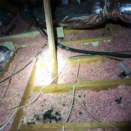 A picture of an attic with a lot of wires and insulation.