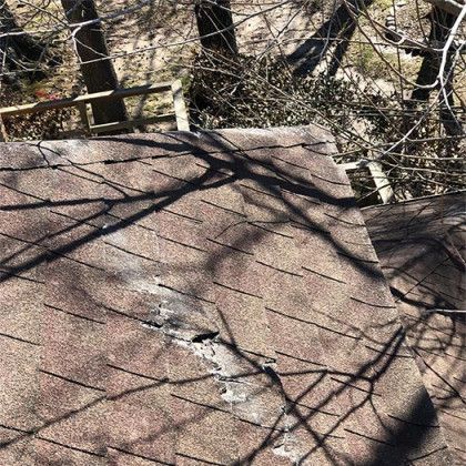 A roof with a hole in it and trees in the background.