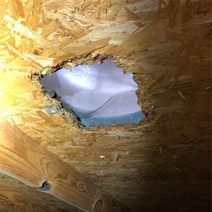 A hole in the ceiling of a house with a light coming out of it.