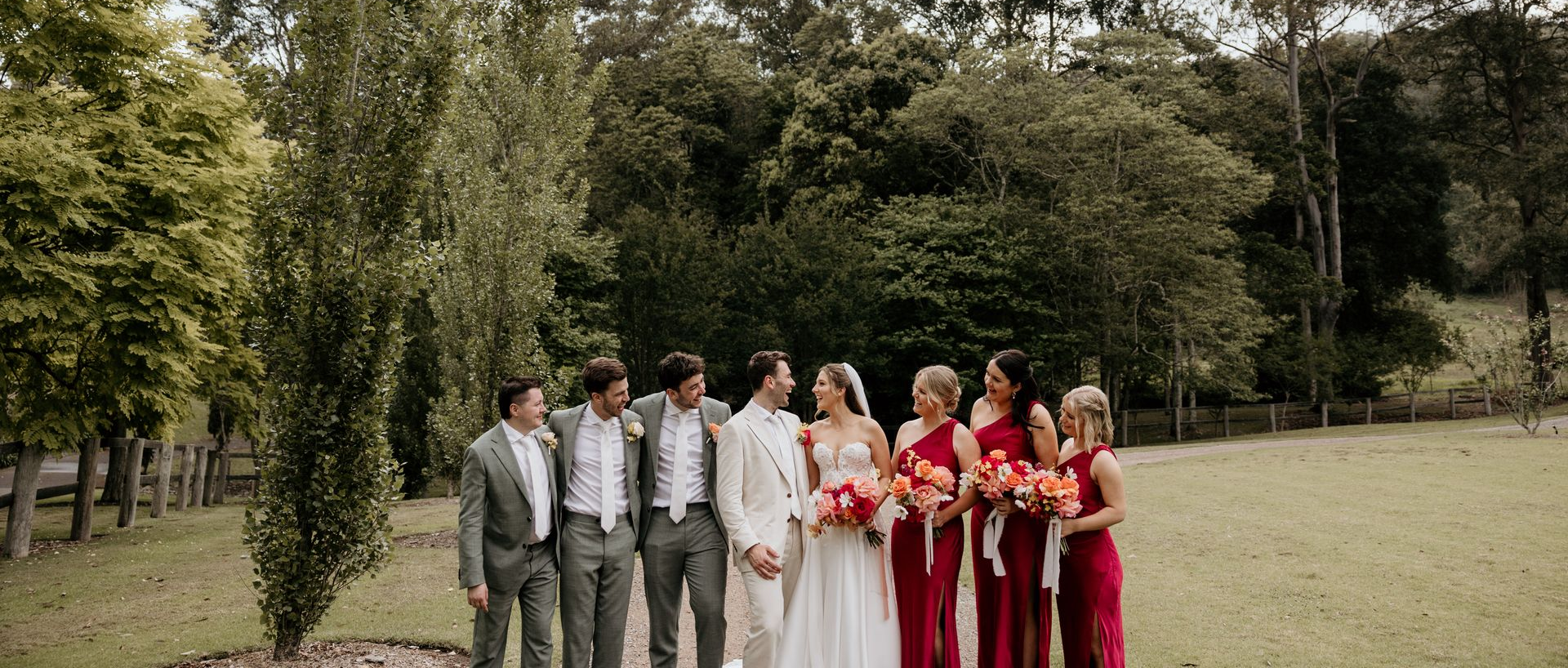 Bridal party celebrating in a grassy field with trees.