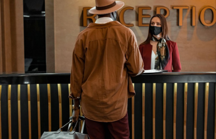 Um homem de chapéu está parado na recepção de um hotel.