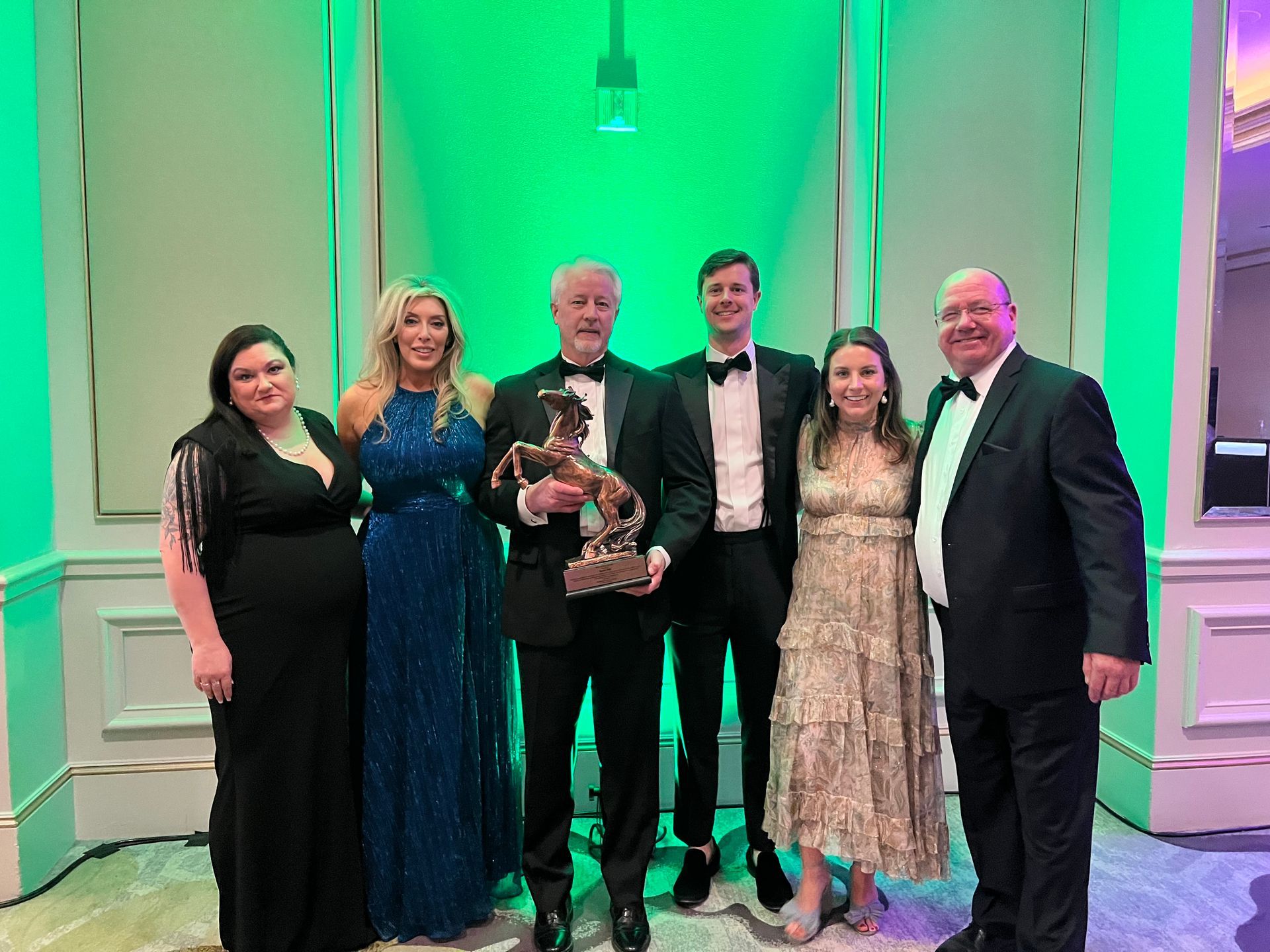 A group of people are posing for a picture in a room with green lights.