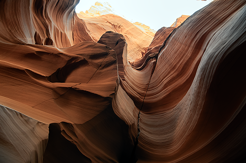 Sunlit sandstone canyon with smooth, wavy rock formations in warm orange and brown tones