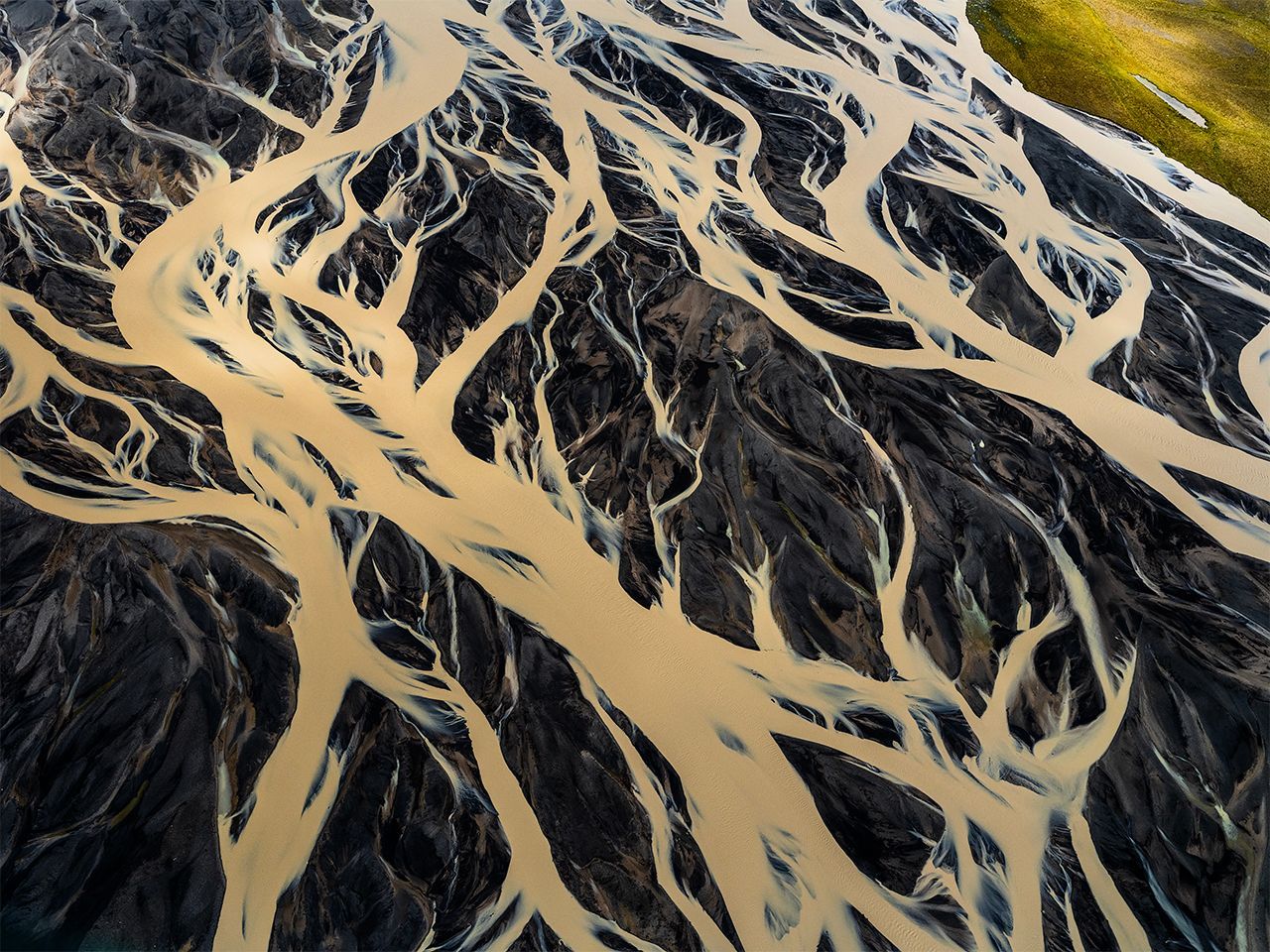 Aerial view of dark river channels cutting through tan sandbars