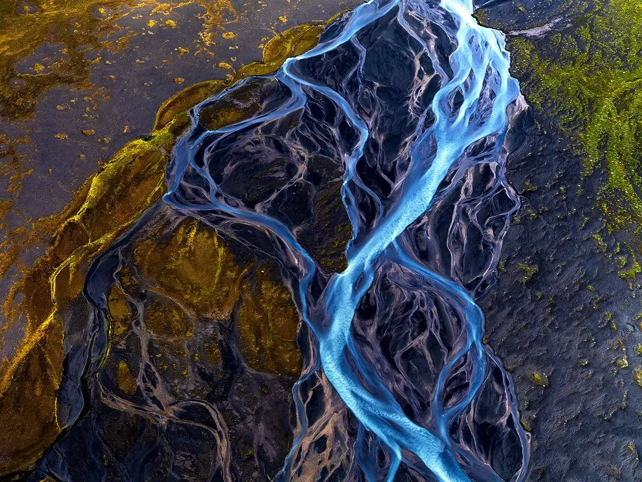 Blue water streams over dark rocks on a textured golden-brown ground